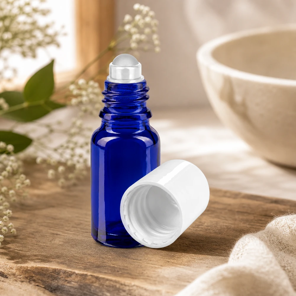 Roll-on-flesje van 10 ml in kobaltblauw met roestvrijstalen balletje en witte dop in een natuurlijke sfeer