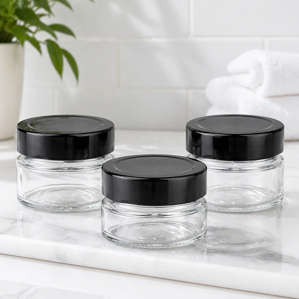 Drie ronde potjes van 80 ml met zwarte BasicSeal deksels UNiTWIST op wit marmeren blad Sfeer badkamer leeg