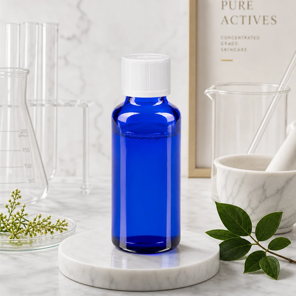Farmaceutische druppelfles van blauw glas, 30 ml, met een inzetstuk van 1,2 mm, naast een vijzel en stamper van marmer