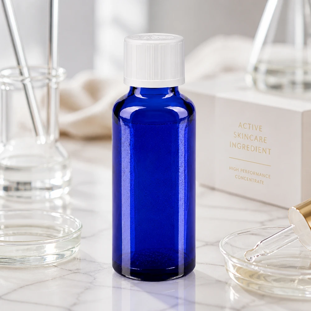 Kleine blauwe apothekersfles van 30 ml met een witte schroefdop naast de Active Skincare Ingredient Box