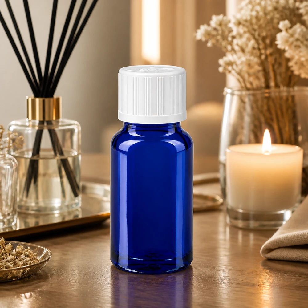 Blauwe glazen fles van 10 ml met kindveilige sluiting naast een brandende kaars en gedroogde bloemen