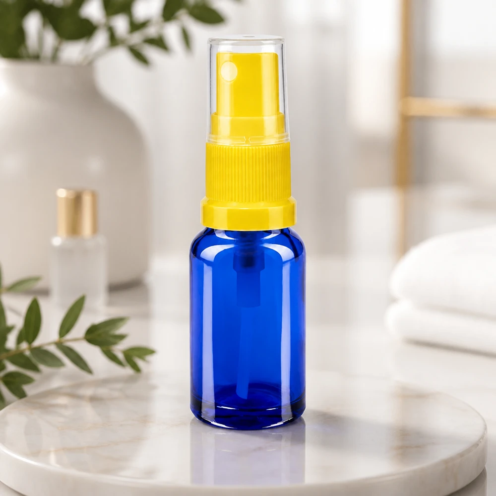 Blauwe glazen flessen 10ml met geel pompverstuiver Compacte blauwe glazen fles van 10 ml met UV-bescherming en een gele fijne verstuiver, STD-formaat