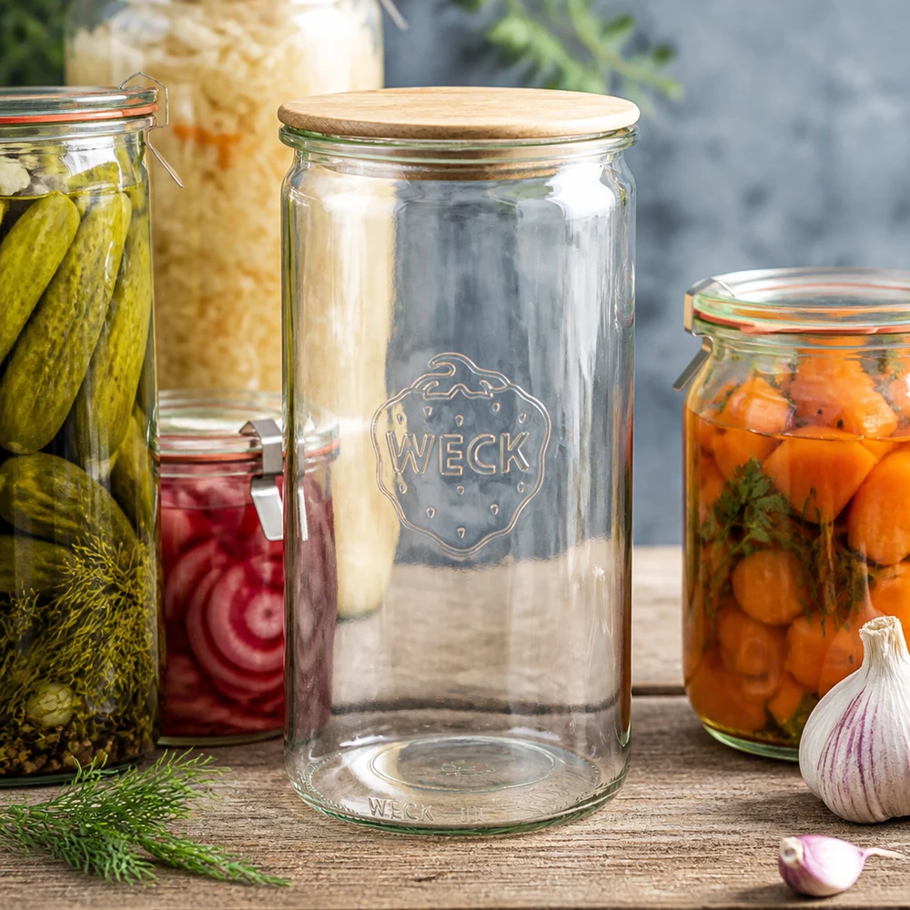 1590ml cilinderglas WECK RR100 met hout deksel WECK Zylinderglas 1590ml RR100 mit Holzdeckel zwischen Einmachgläsern mit Gurken Karotten und Sauerkraut auf Holztisch