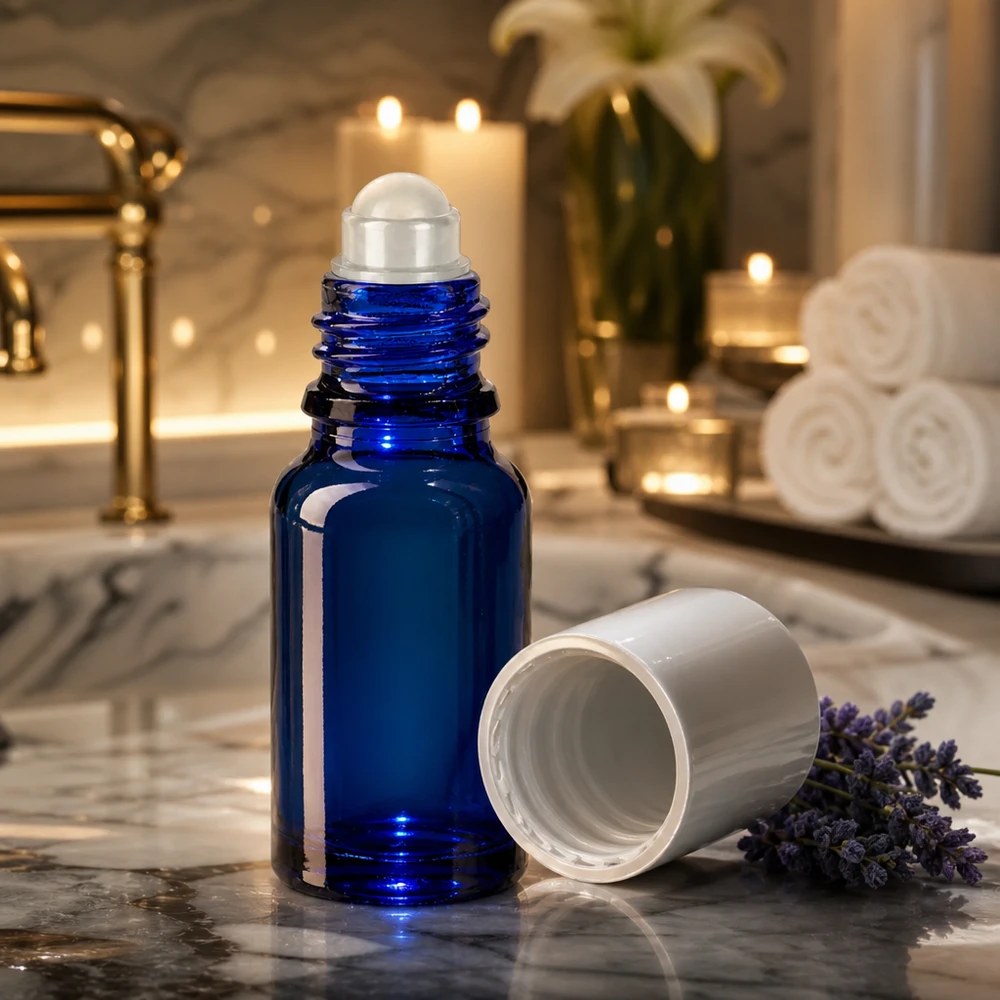 Apothekersflesje blauw 10ml roll-on cap wit Blauw roll-on-flesje van 10 ml van apothekersglas naast lavendel op een grijze marmeren steen