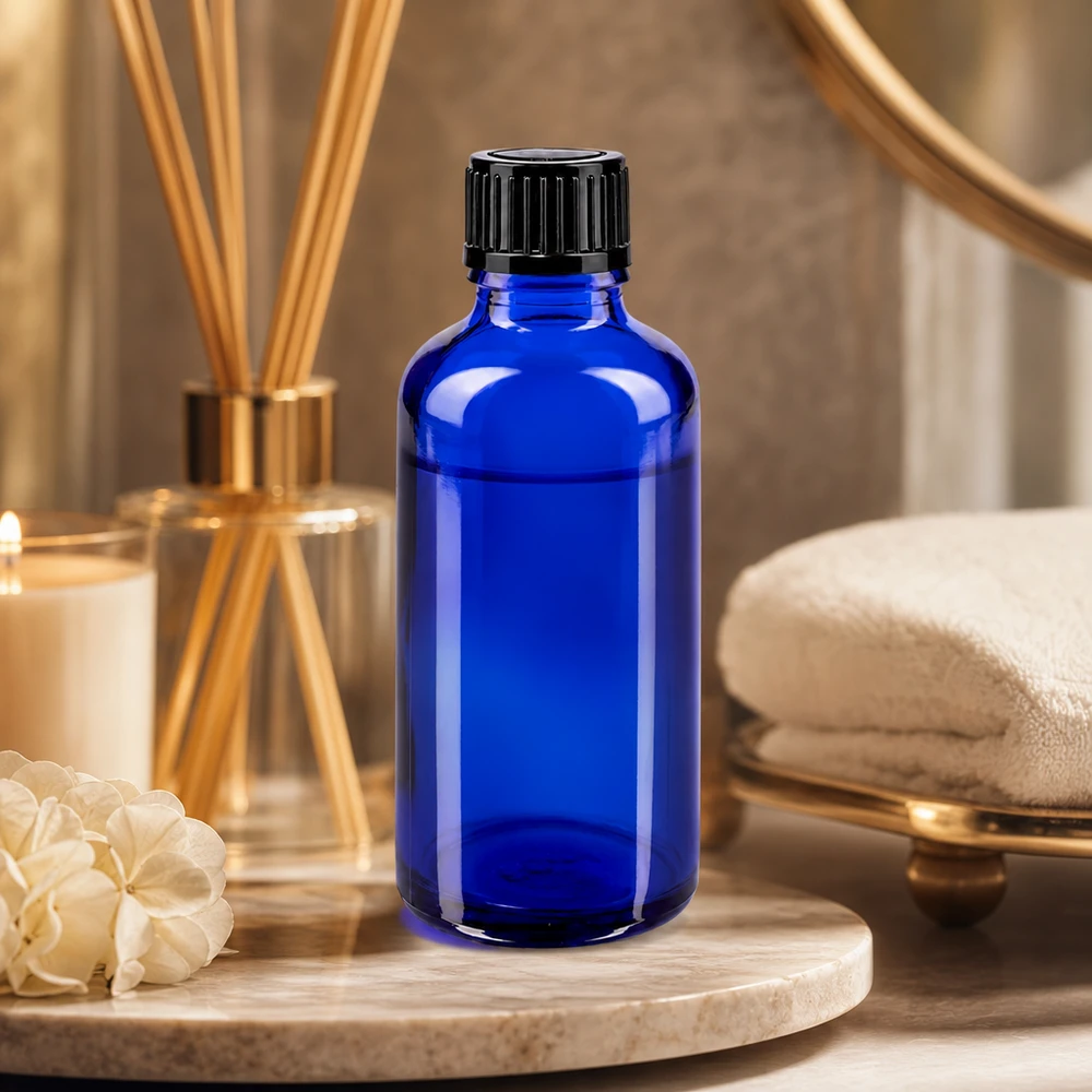 Blauwe apothekersflesje van 50 ml STD met zwarte druppeldop op een marmeren dienblad met kamerparfum