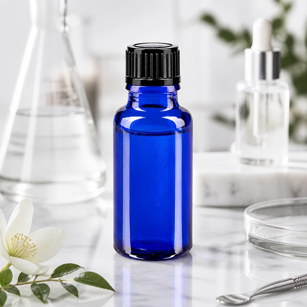 Blauwe glazen flessen 20ml met zwart druppelsluiting 1mm St Een blauw flesje van 20 ml van apothekersglas naast een Erlenmeyer-kolf en een jasmijnbloem