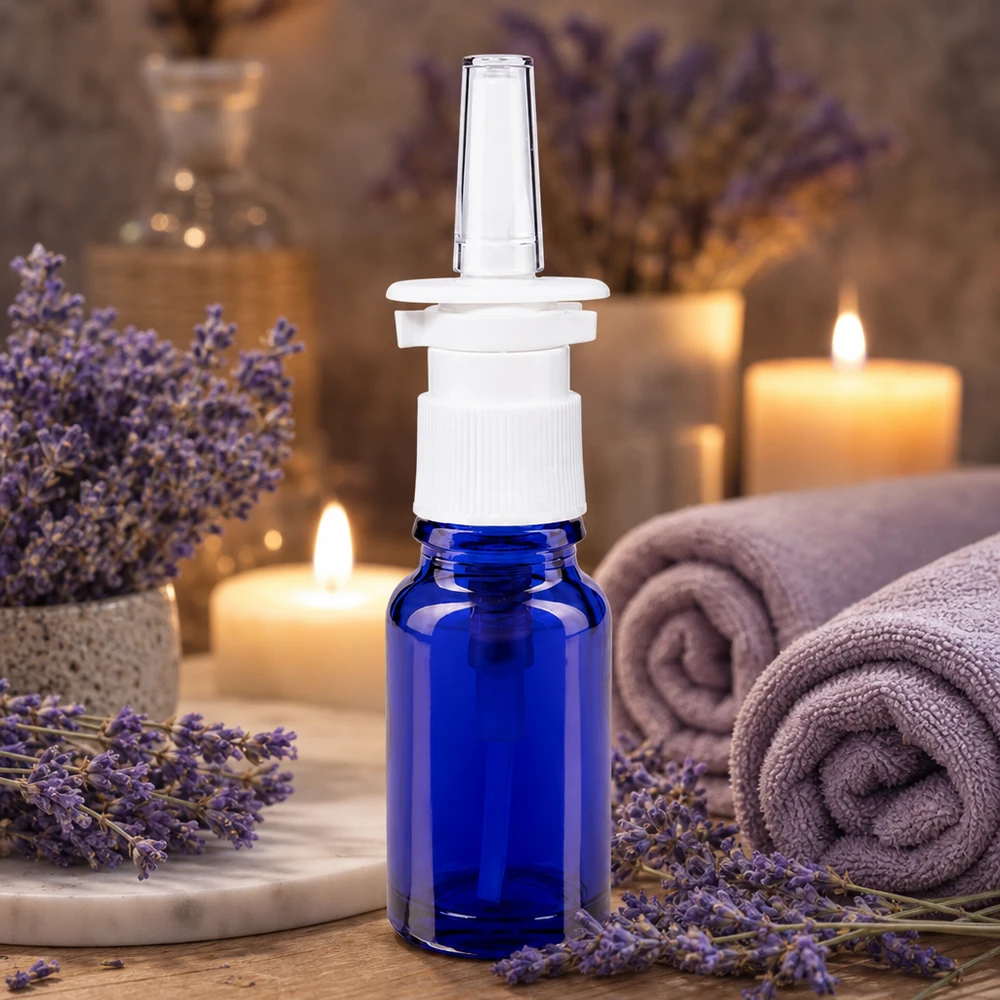 Blauwe glazen flessen 10ml met neusverstuiver Kleine neussprayfles van 10 ml in kobaltblauw met een witte dop, op een houten ondergrond met kaarsen