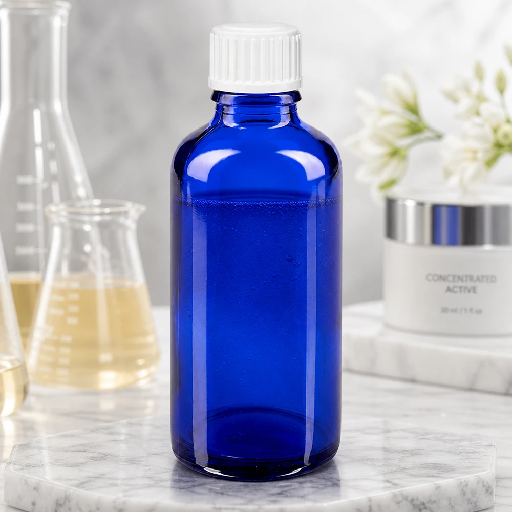 Blauwe glazen medicijnfles van 50 ml met witte standaarddop op een marmeren ondergrond