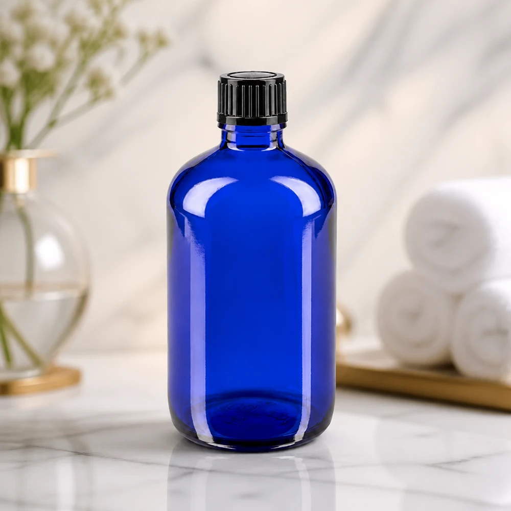 Blauwe glazen flessen 100ml met zwart schroefsluiting St Blauwe medicijnfles van 100 ml van UV-bestendig glas met een zwarte standaarddop tegen een marmeren achtergrond