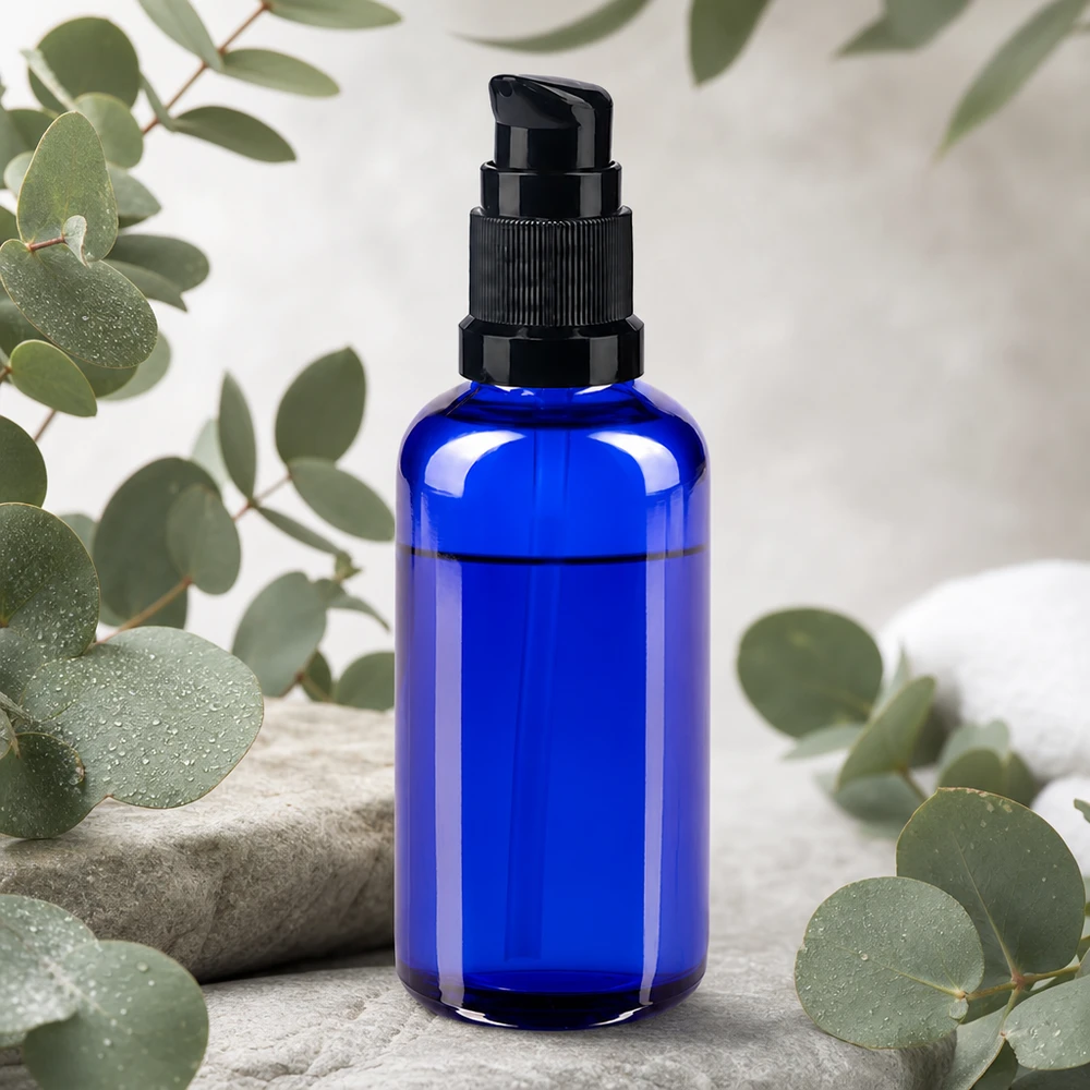 Blauwe glazen flessen 50ml met zwart pompsluiting Blauwe glazen pot van 50 ml met een STD-pomp in zwart, decoratief gearrangeerd op natuursteen