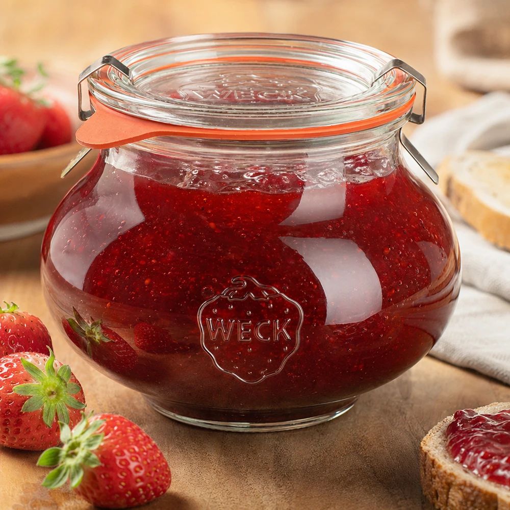 WECK decoratieve pot 560ml gevuld met zelfgemaakte aardbeienjam, klapdeksel gesloten, omringd door vers fruit en groenten.