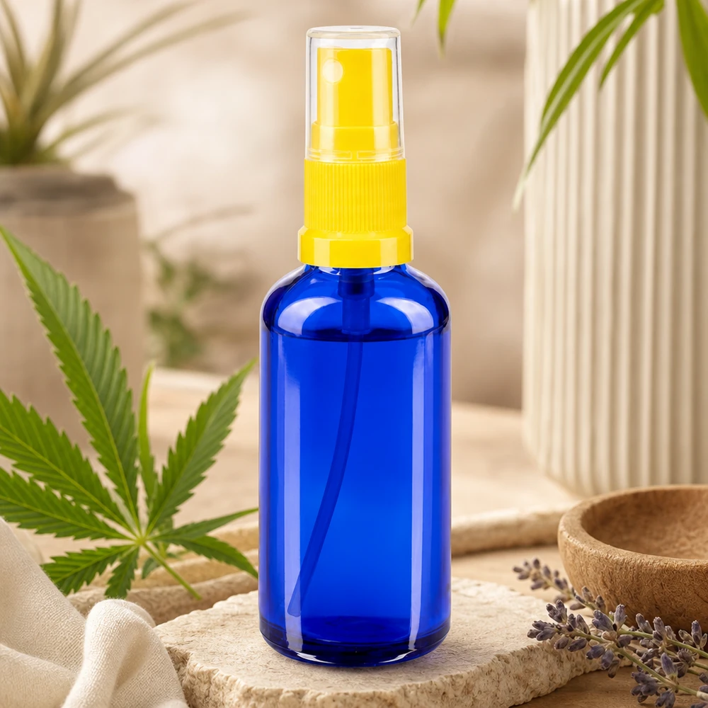 Cilindrische blauwe glazen fles van 50 ml met een gele fijne verstuiver en lavendelversiering