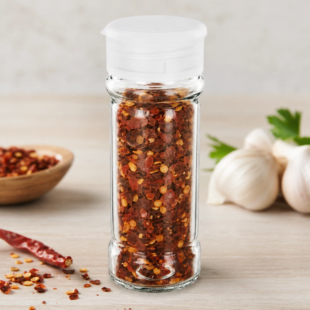 Zout-/kruidenpotje 100 ml met strooier, wit Klein kruidenpotje van 100 ml met witte strooier, gevuld met rode chilivlokken en knoflook op de achtergrond