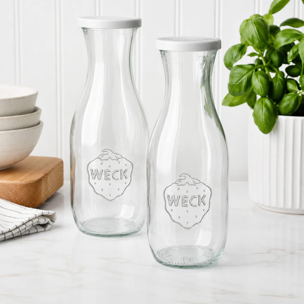 Twee WECK sapflessen 1062ml met witte deksels in moderne keuken naast schalen en basilicumplant