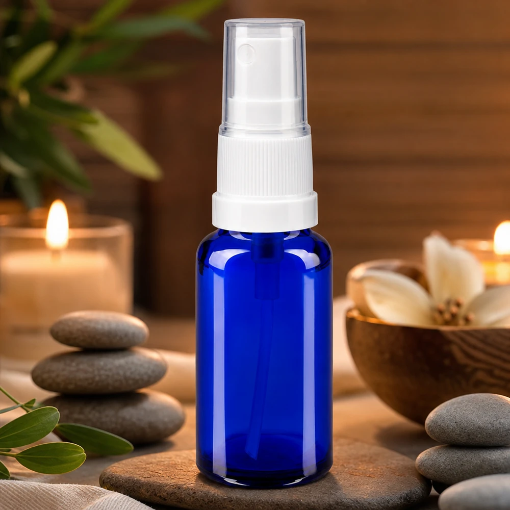 Blauw minispuitflesje van 20 ml van apothekersglas met wit pompmechanisme naast zen-stenen
