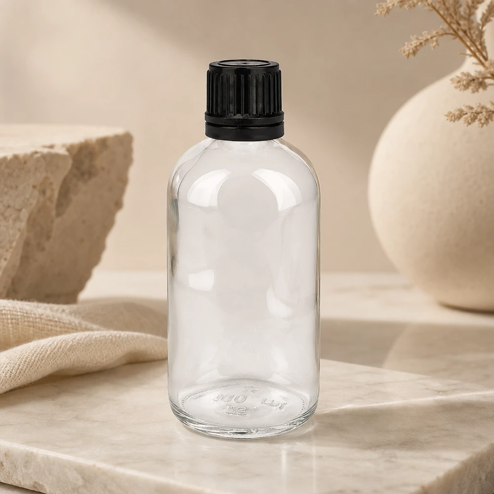 100ml (Globul)Flas. 8mm GR s. STD ClearL. UT18/100 Cilindrische glazen fles van 100 ml met een geribbelde zwarte dop op een marmeren achtergrond