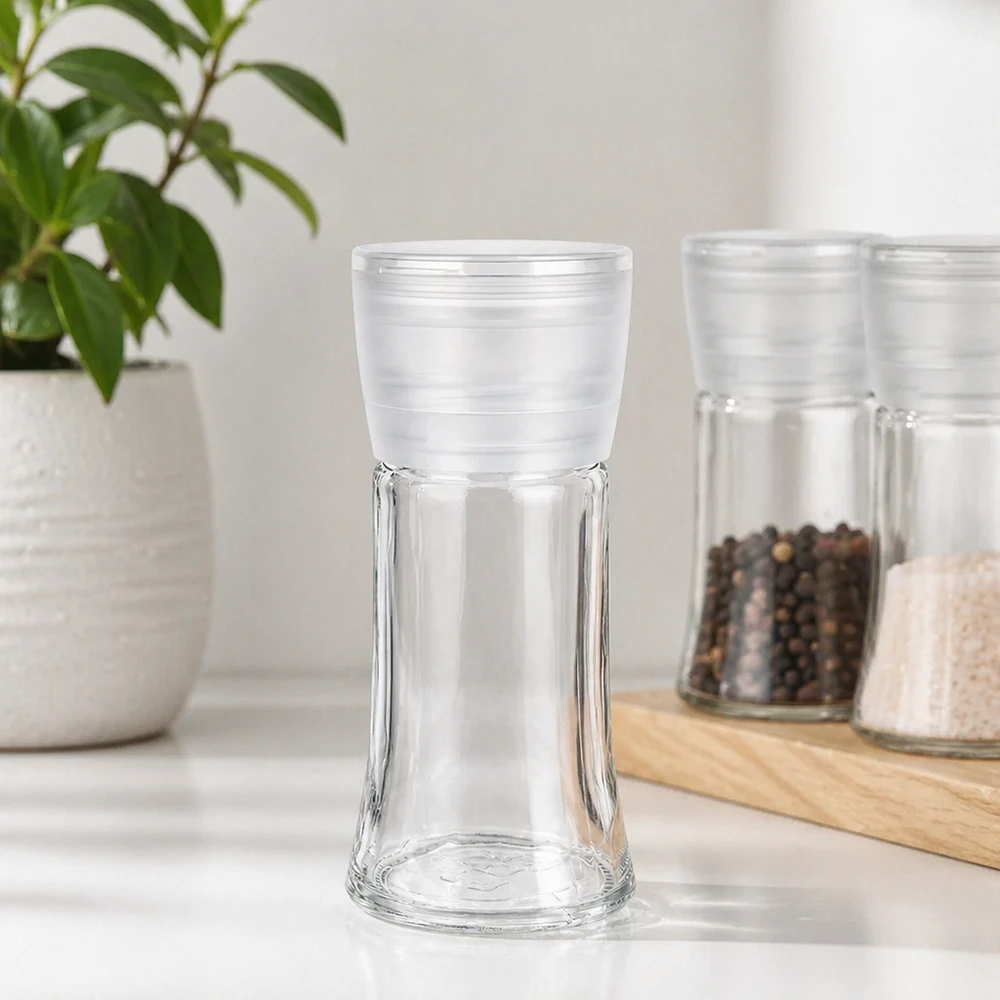 Leeg kruidenpotje van 95 ml met witte Vario-molen naast peperkorrels en zout op een houten plankje