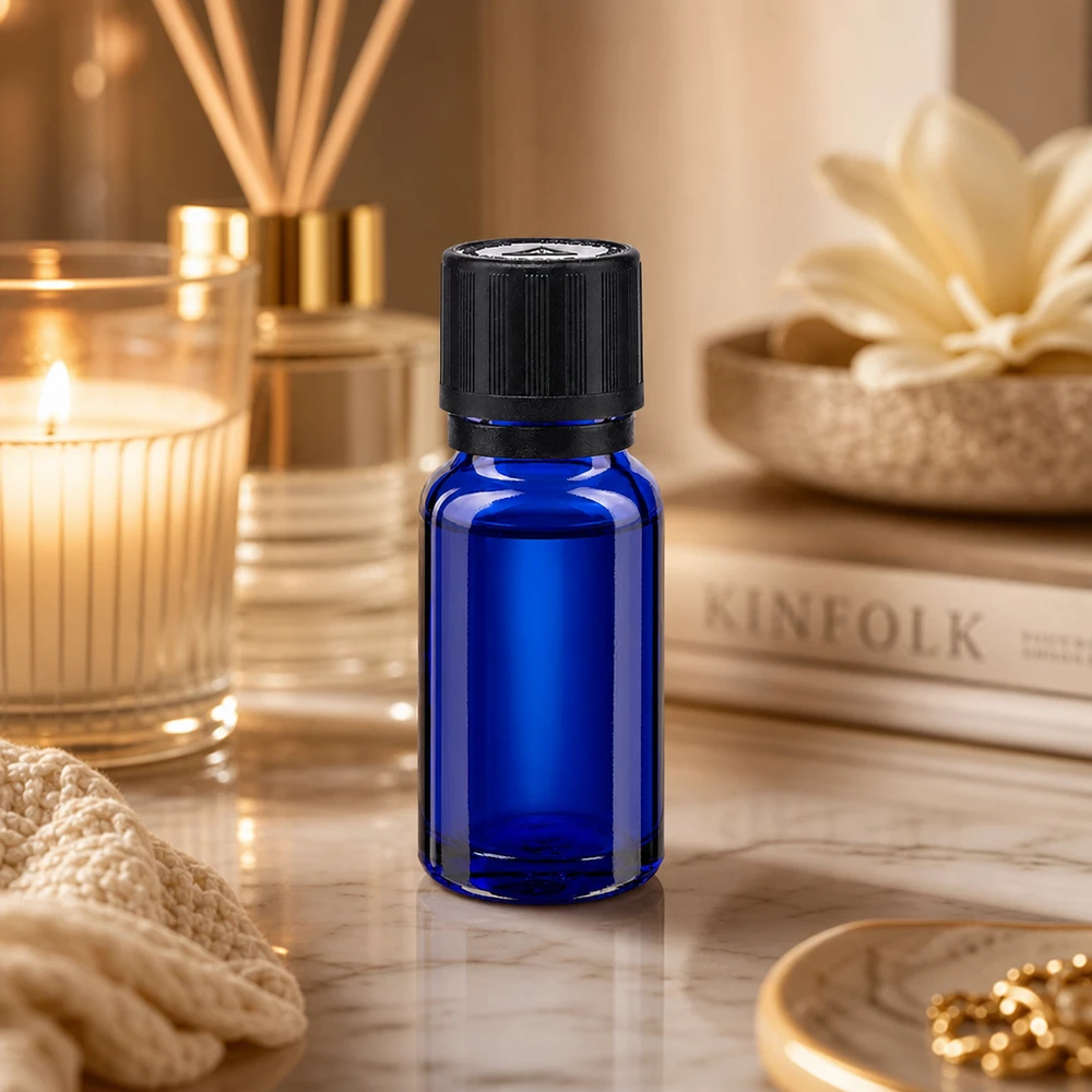 Zonwerende fles van 10 ml, blauw met een zwarte OV-sluiting, omringd door spa-accessoires op marmer