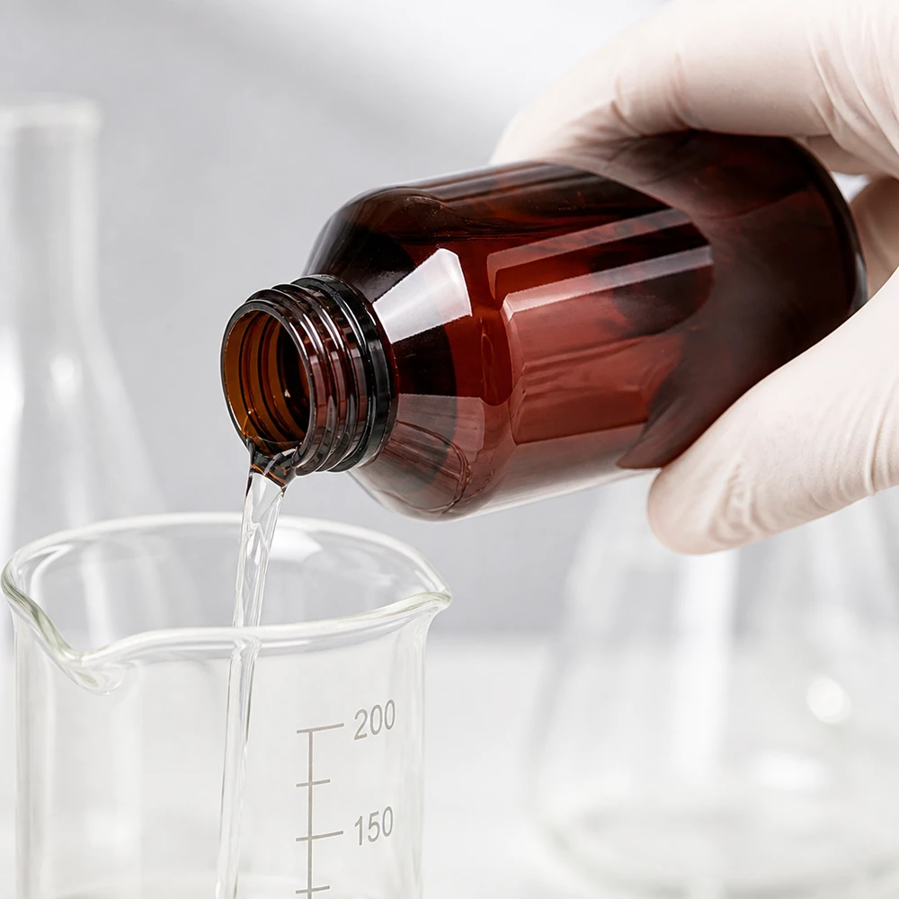Nauwkeurige dosering van vloeistof uit een bruine PET-fles van 100 ml in een maatbeker