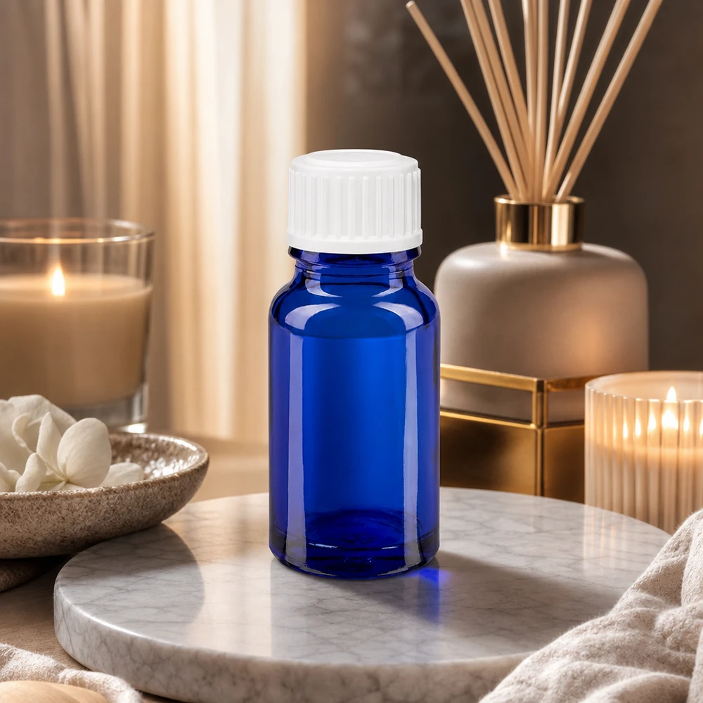 Blauwe glazen flessen 10ml met wit sluiting Kleine blauwe glazen flesje van 10 ml met een witte standaarddop, naast een reeddiffuser en geurkaarsen