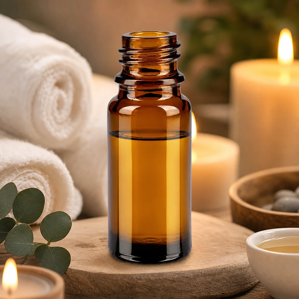 10ml bruin apothekersflesje ApoGlas met etherische oliën tussen witte handdoeken en brandende kaarsen