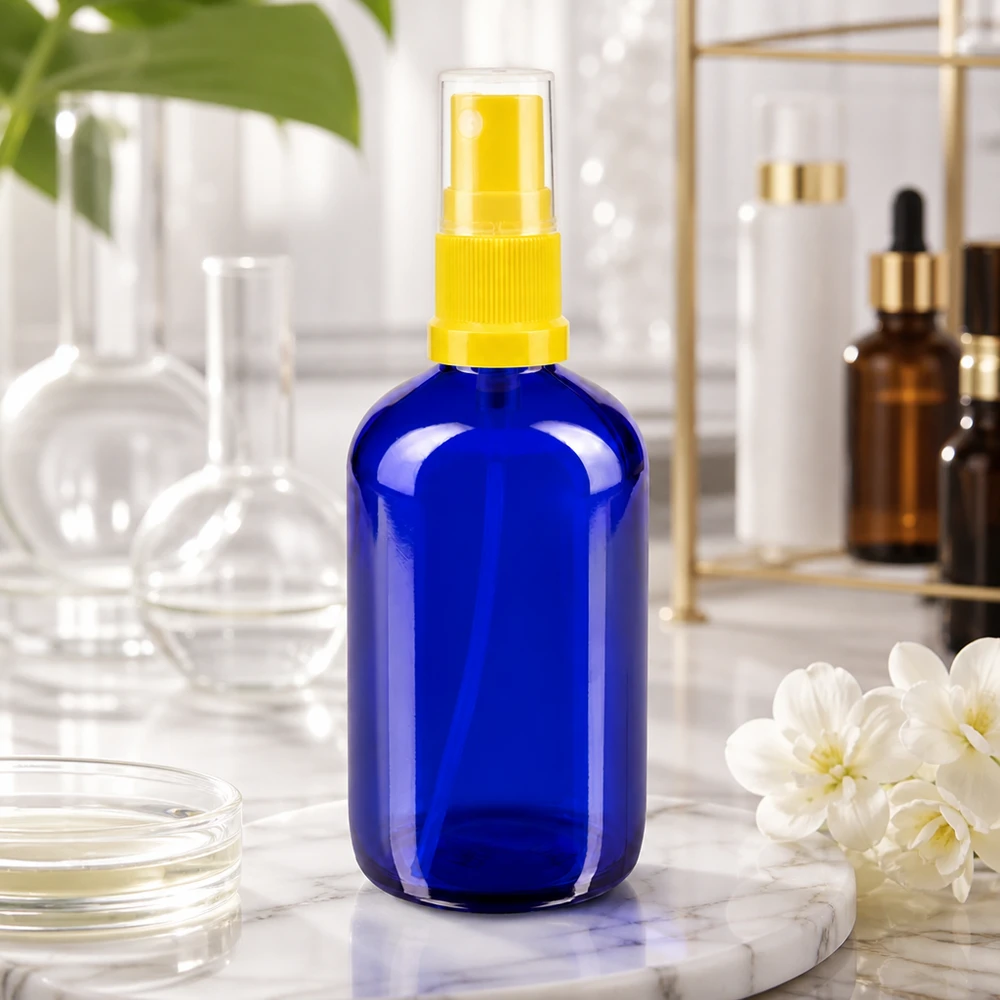 Blauwe glazen flessen 100ml met geel pompverstuiver Compacte ronde fles van 100 ml, kobaltblauw met gele fijne verstuiver, in lichtbeschermend apothekersglas