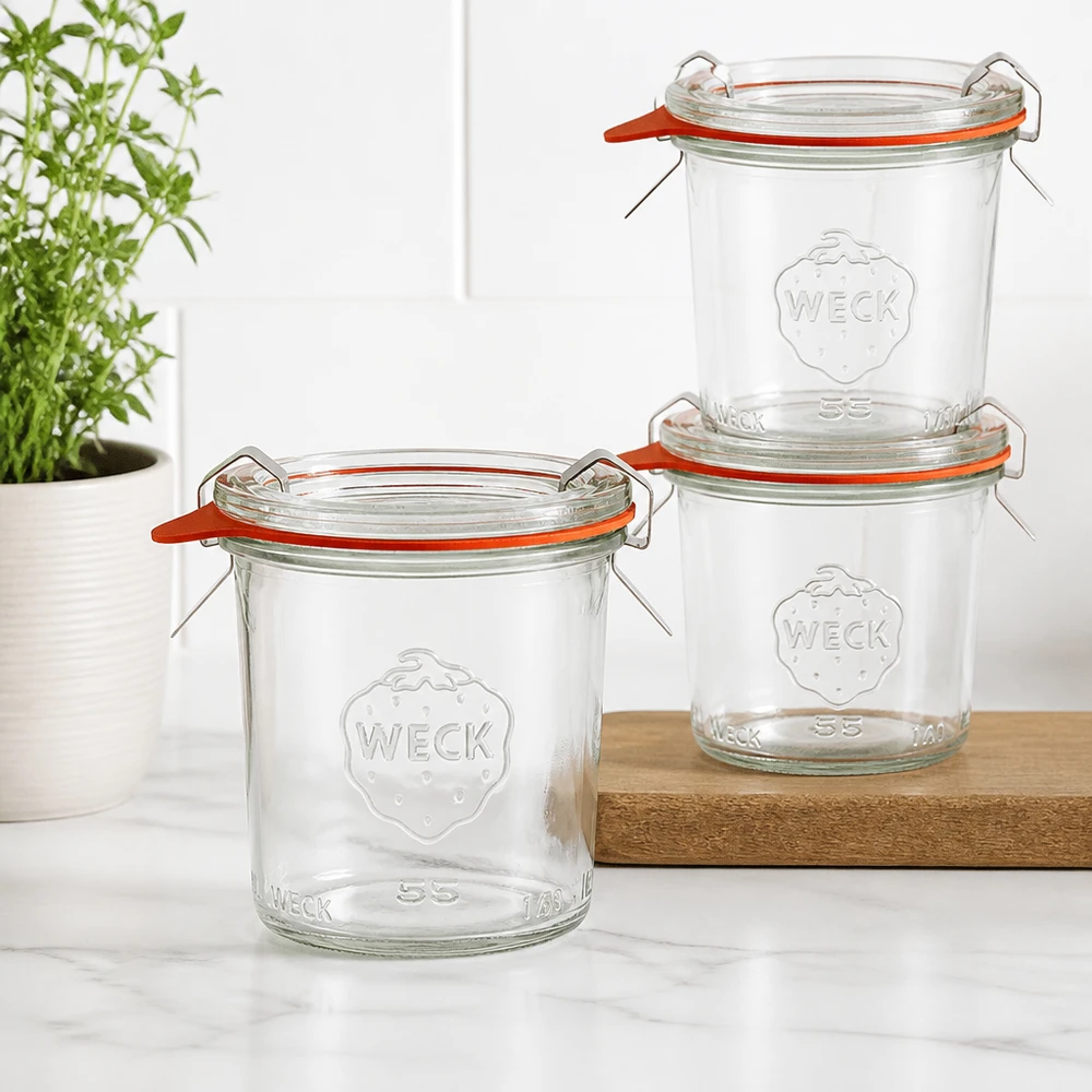 Drie WECK 140ml RR60 bekers gestapeld op een houten plank in een moderne keuken met een groene plant op de achtergrond